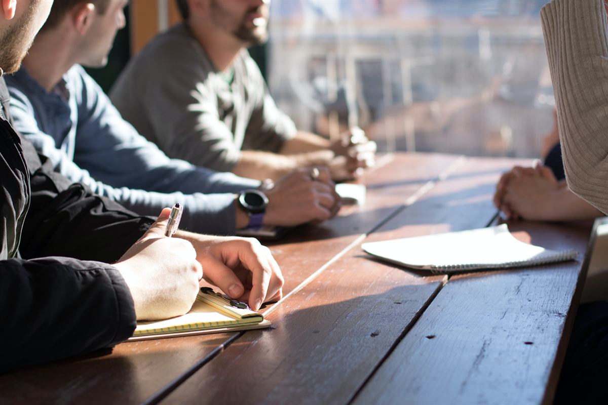 A team meeting around a table with laptops